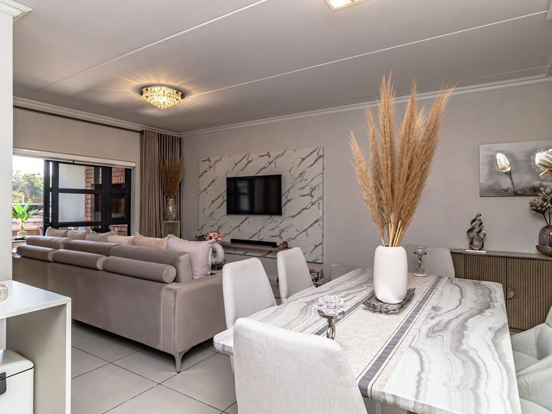 A modern open-plan living and dining area featuring a marble-look feature wall, tiled flooring, and seamless access to an outdoor space.