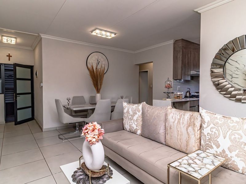 An open-plan living and dining area featuring tiled flooring, modern recessed lighting, and a functional kitchen space with built-in cabinetry.