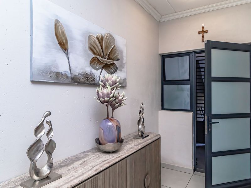 A bright and welcoming entrance area featuring tiled flooring, decorative cornicing, and a modern frosted glass security door.