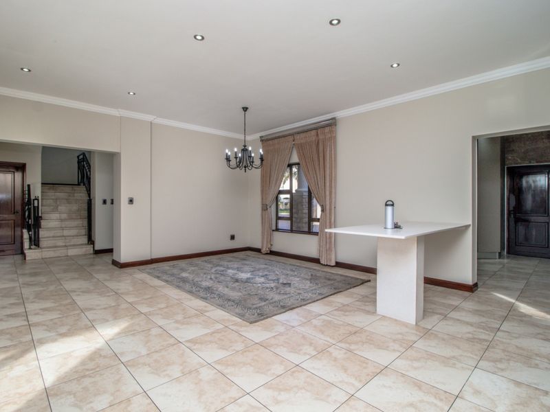 Spacious living area featuring tiled flooring, recessed downlights, crown molding, and a built-in breakfast bar, with an adjacent staircase.