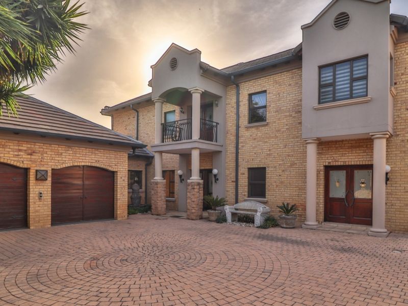 Front elevation of a double-story cluster home featuring a paved circular driveway, double garage, and a covered entrance with balcony above.