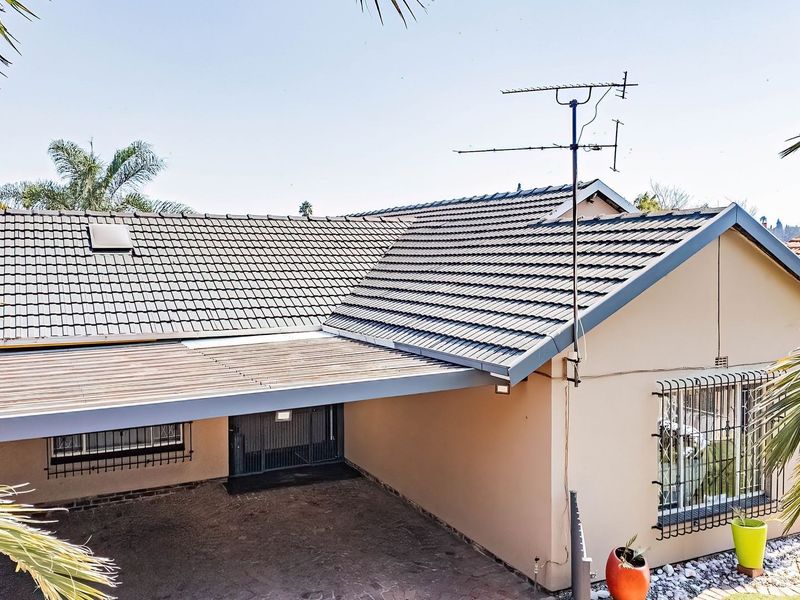 Front elevation of a residential house featuring a tiled roof, integrated carport, and security bars on windows.