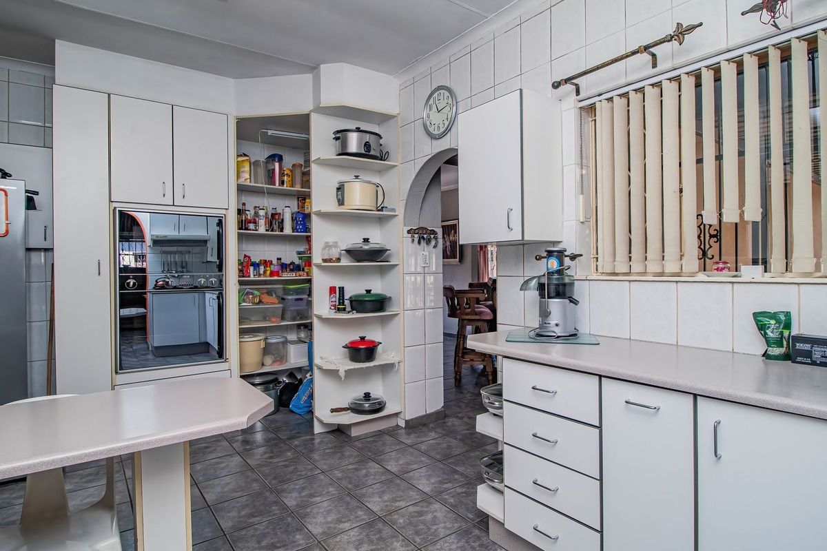 Functional kitchen featuring white cabinetry, laminate countertops, tiled splashbacks, built-in oven, and an integrated open pantry area with tiled flooring.