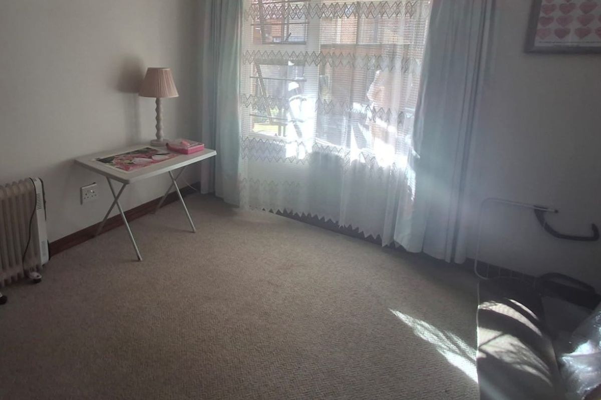 A bedroom featuring carpeted flooring and natural light through a window with curtain tracks.