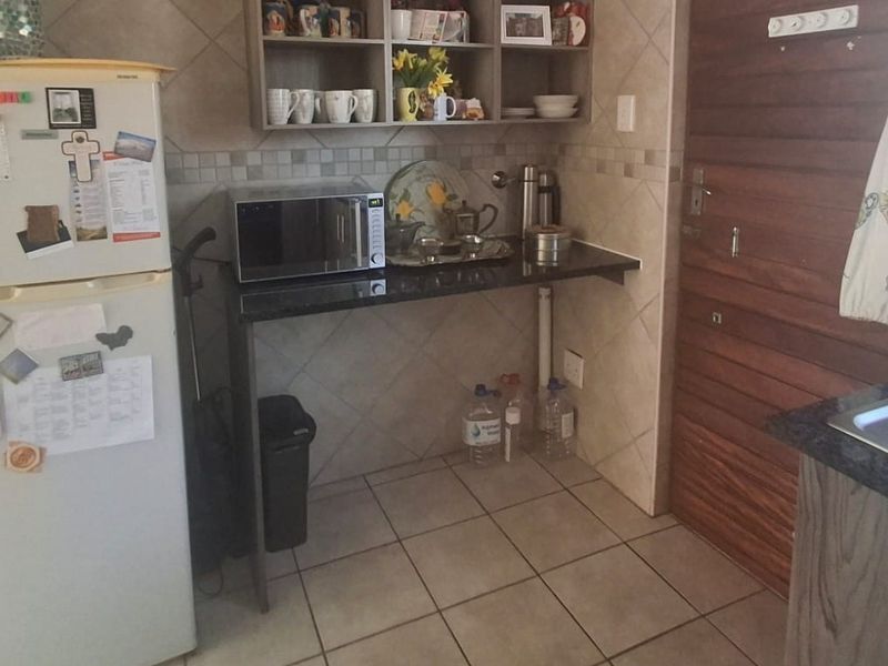 A functional scullery area featuring granite countertops, tiled splashbacks, and built-in shelving, providing additional workspace and storage adjacent to the main kitchen.