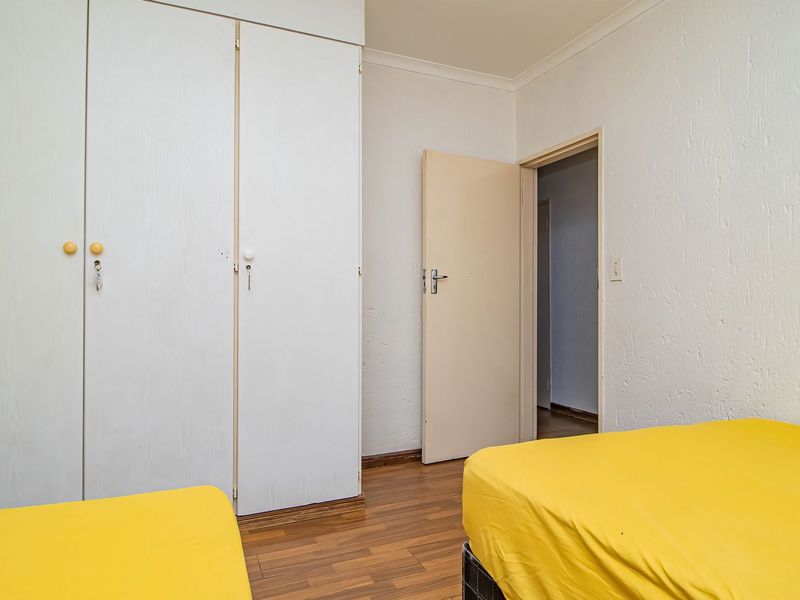 A bedroom featuring built-in cupboards, laminate flooring, and a coved ceiling, offering a functional space with neutral finishes.
