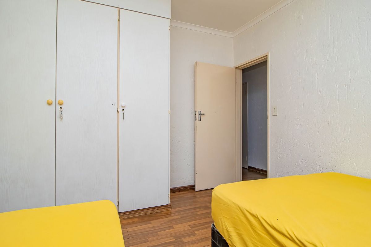A bedroom featuring built-in cupboards, laminate flooring, and a coved ceiling, offering a functional space with neutral finishes.