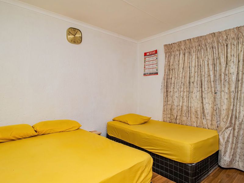A functional bedroom featuring laminate flooring and neutral wall finishes, providing a comfortable space for rest.