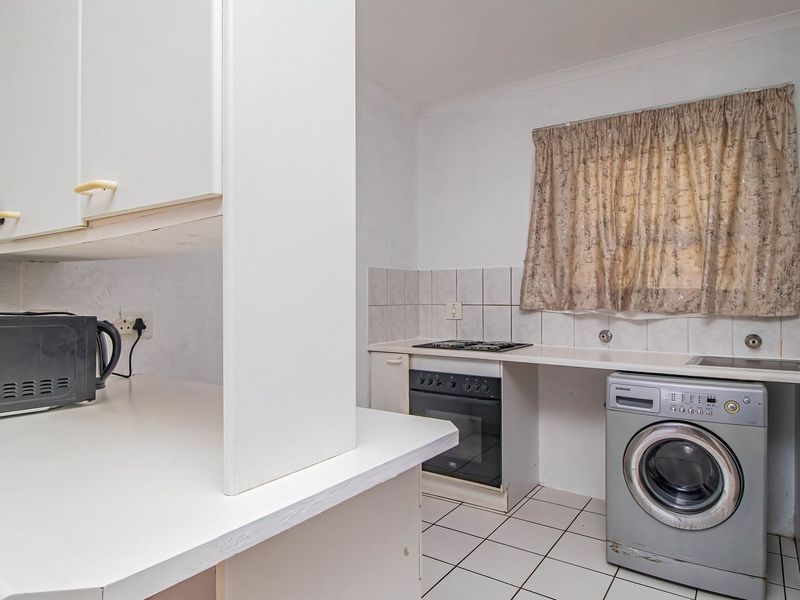A functional kitchen featuring white built-in cabinetry, tiled splashbacks, a built-in oven and hob, and tiled flooring.