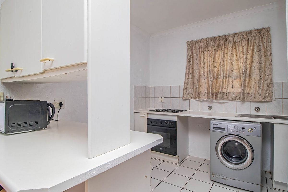 A functional kitchen featuring white built-in cabinetry, tiled splashbacks, a built-in oven and hob, and tiled flooring.