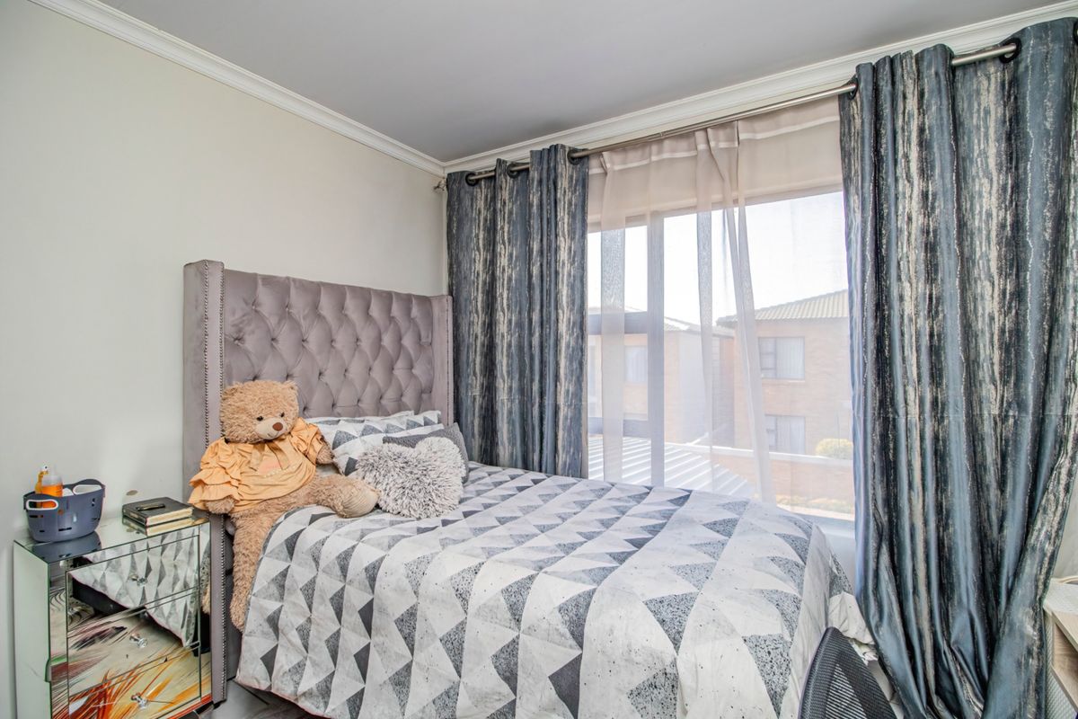 A well-lit bedroom featuring crown molding and a large window with installed curtain rods, offering a comfortable and functional living space.