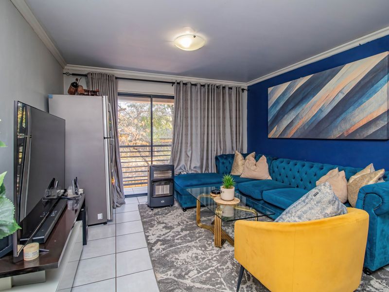 A comfortable living room featuring tiled flooring, a bold blue accent wall, and a sliding glass door providing access to an outdoor balcony area.