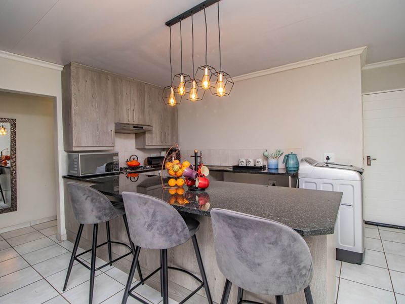 Modern kitchen featuring granite countertops, built-in cabinetry, tiled flooring, and stylish pendant lighting, providing a functional and contemporary cooking and dining space.