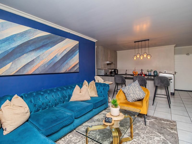 An open-plan living and kitchen area featuring a breakfast bar, modern cabinetry, and tiled flooring, creating a functional and connected living space.