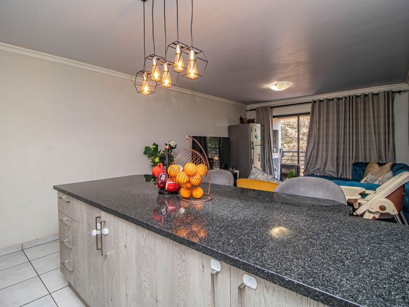 Open plan living area featuring a modern kitchen island with granite countertops, tiled flooring, and direct access to an outdoor balcony.