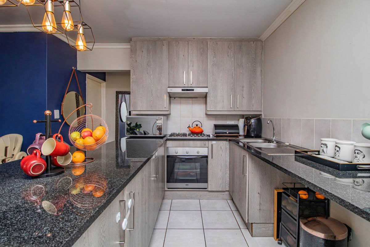 Modern kitchen featuring granite countertops, laminate cabinetry, built-in oven, gas hob, and tiled flooring in a functional U-shaped layout.