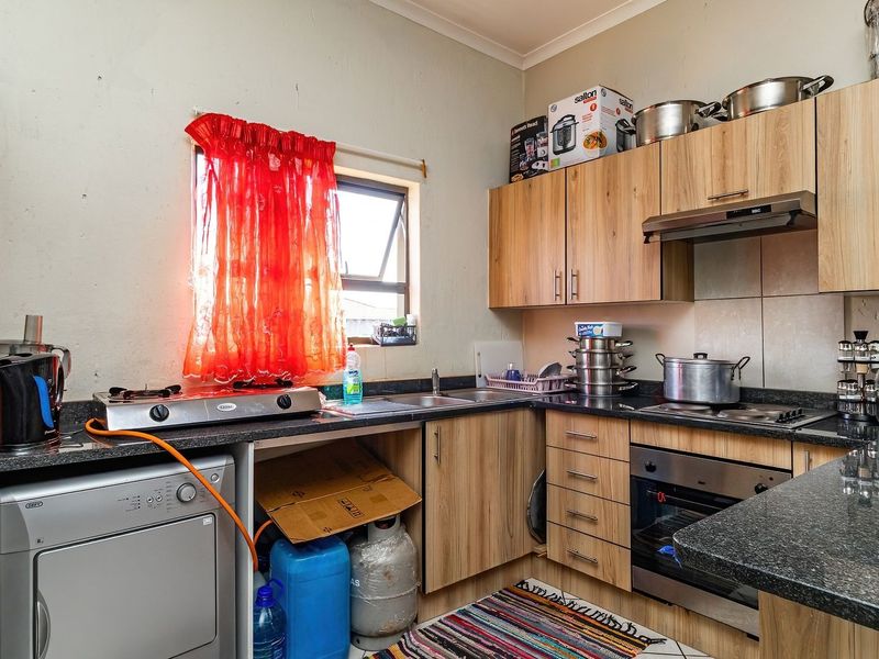 Compact kitchen featuring laminate cabinetry, granite countertops, built-in oven, gas hob, and extractor fan, providing functional preparation and cooking space.
