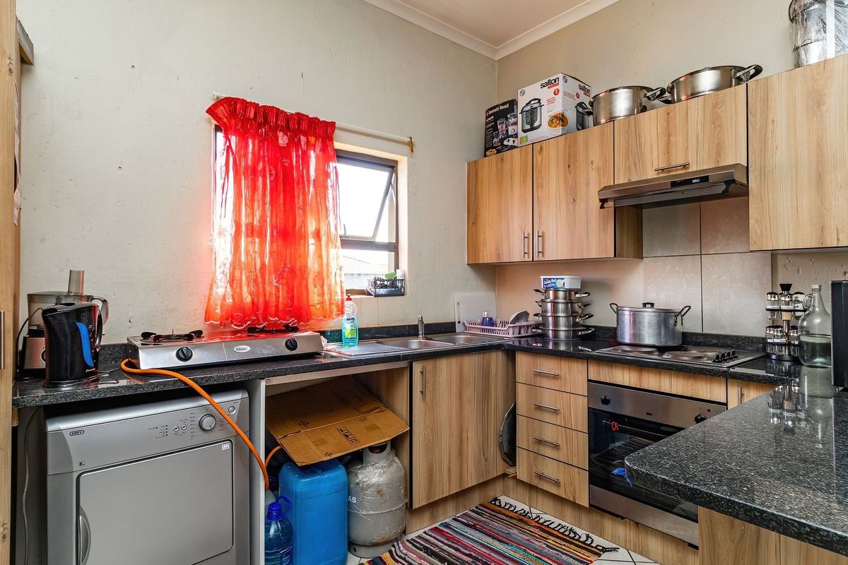 Compact kitchen featuring laminate cabinetry, granite countertops, built-in oven, gas hob, and extractor fan, providing functional preparation and cooking space.