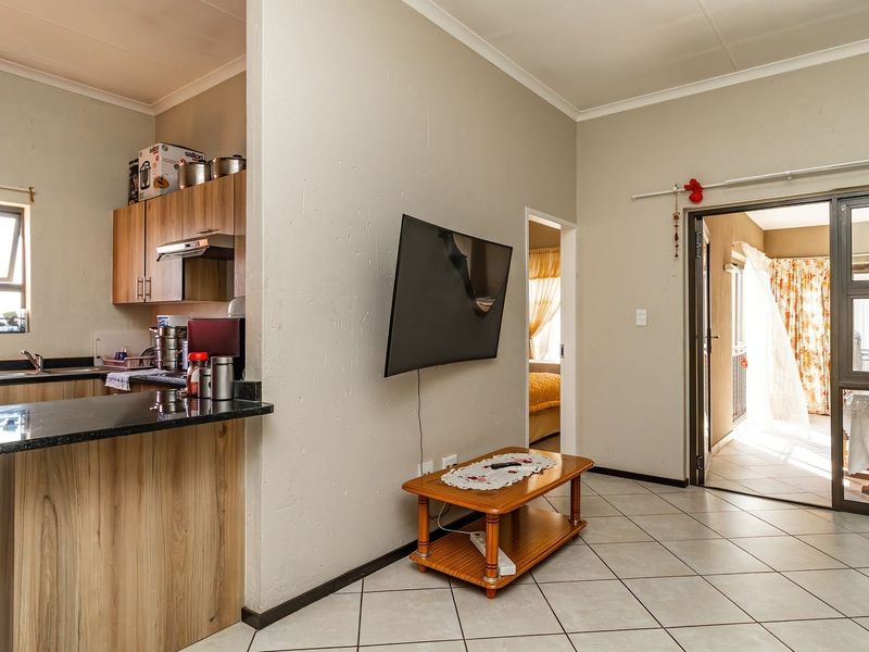 Open plan living area featuring a compact kitchen with granite countertops, tiled flooring, and direct access to an outdoor patio through sliding glass doors.