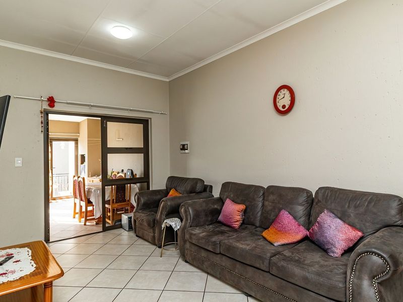 A living room featuring tiled flooring, coved ceilings, and a sliding glass door providing access to an adjacent dining area.