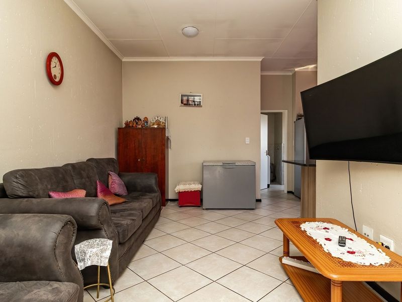 A functional living room featuring tiled flooring and a wall-mounted television, providing a comfortable and practical space for relaxation.
