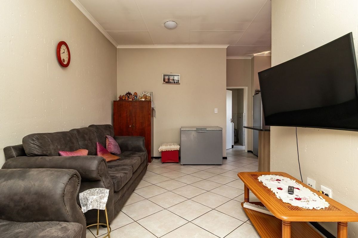 A functional living room featuring tiled flooring and a wall-mounted television, providing a comfortable and practical space for relaxation.