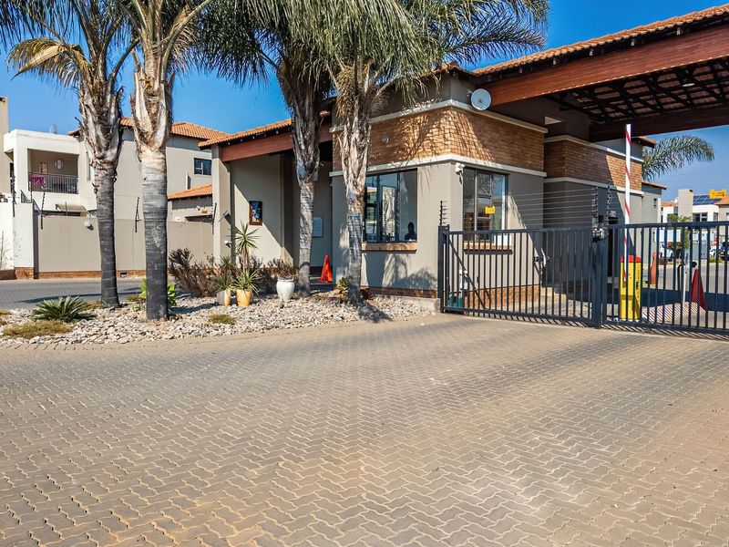 The entrance to Waterfall Park featuring a secure gated access point with brick paving, electric fencing, and a dedicated guard house.