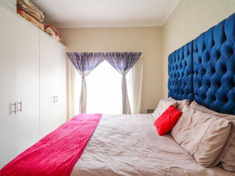 A well-maintained bedroom featuring a large built-in wardrobe with overhead storage and neutral wall finishes.