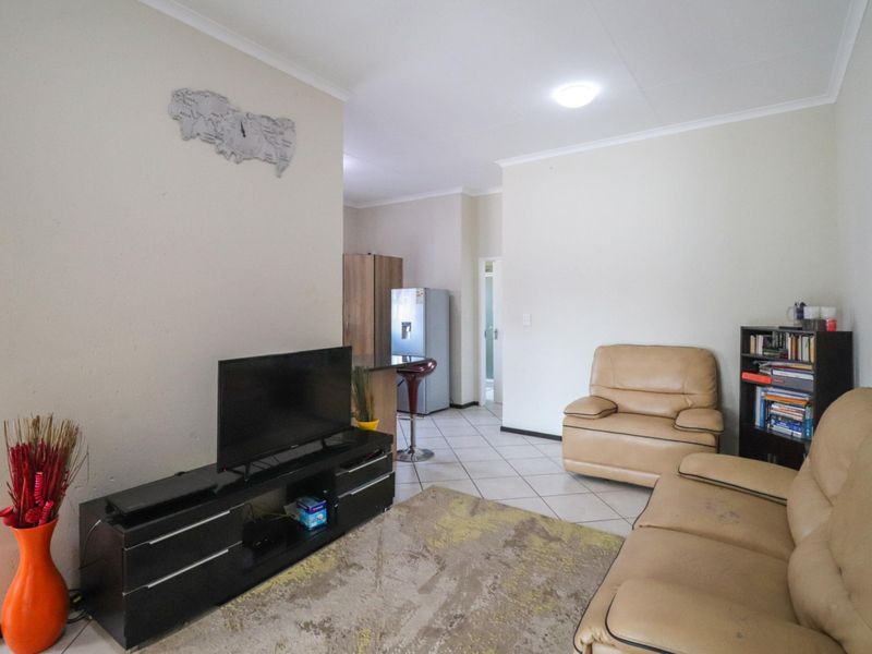 Open-plan living area featuring tiled flooring and coved ceilings, seamlessly connecting to a functional kitchen space.