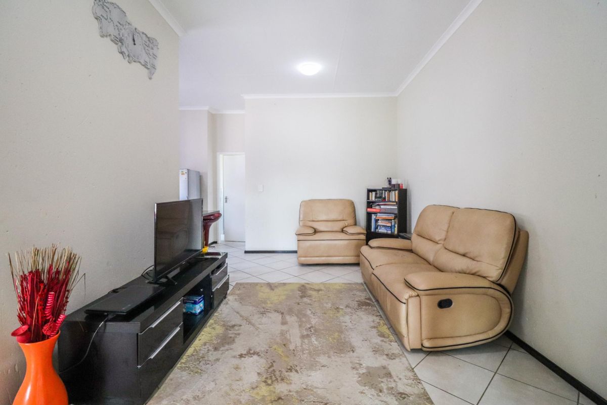 A functional living room featuring tiled flooring and neutral wall finishes, providing a clean and simple space for relaxation.