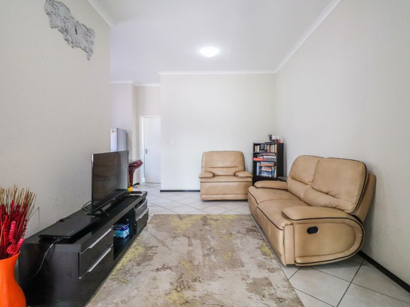 A functional living room featuring tiled flooring and neutral wall finishes, providing a clean and simple space for relaxation.