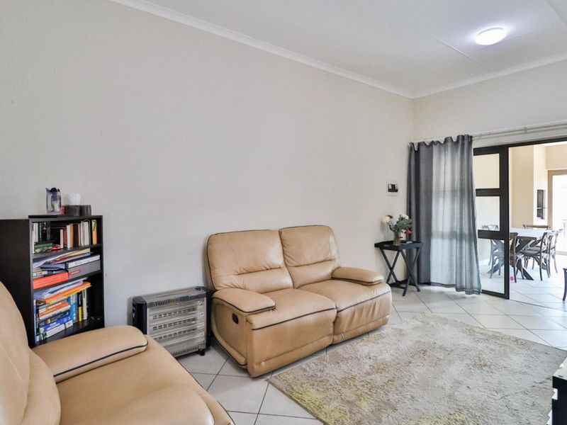 A living room featuring tiled flooring and a sliding glass door providing access to an adjacent dining area.