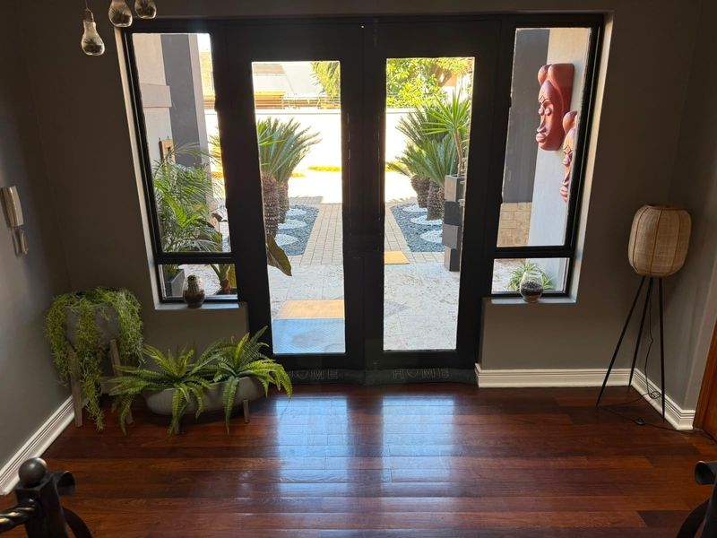 Welcoming entrance foyer featuring polished hardwood flooring and large double glass doors that provide a clear view of the front garden area.