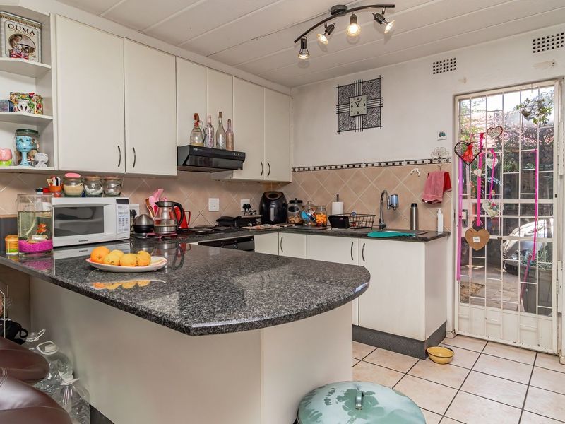 A functional kitchen featuring granite countertops, ample cabinetry, and direct access to the exterior through a security gate.