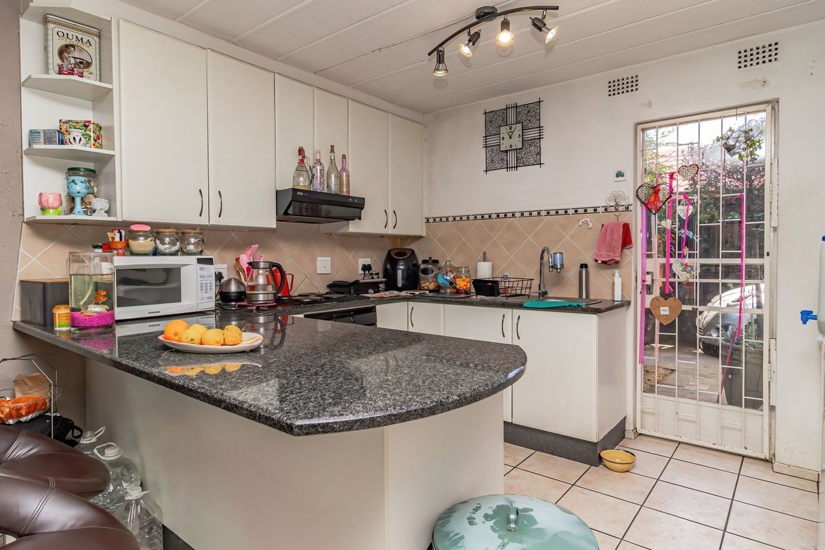 A functional kitchen featuring granite countertops, ample cabinetry, and direct access to the exterior through a security gate.