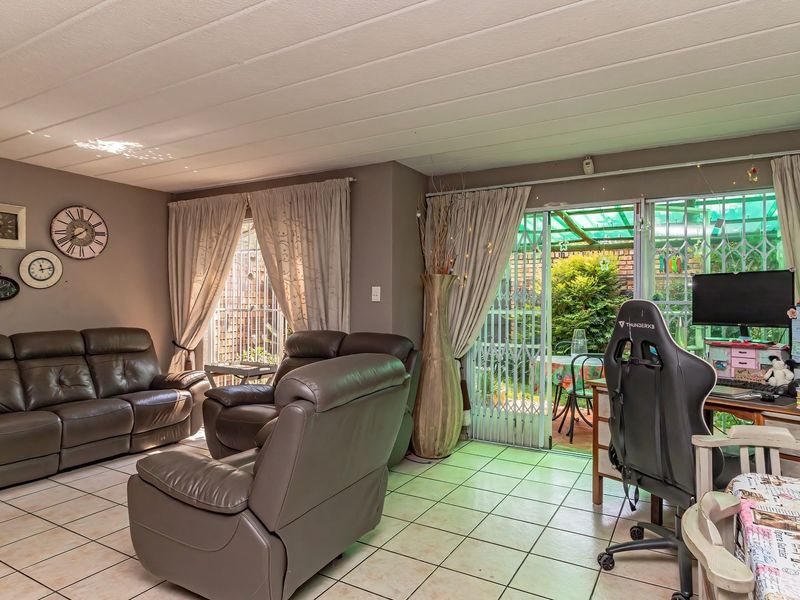 A spacious living room featuring tiled flooring, a tongue and groove ceiling, and a sliding glass door providing access to the outdoor patio area.