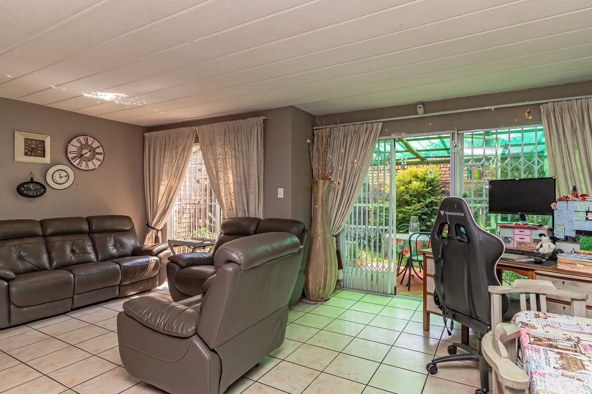 A spacious living room featuring tiled flooring, a tongue and groove ceiling, and a sliding glass door providing access to the outdoor patio area.