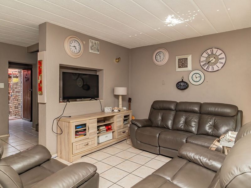 A living room featuring tiled flooring, a recessed wall niche for media storage, and a textured ceiling, providing a functional and comfortable living space.
