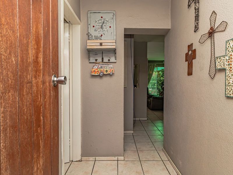 A functional hallway featuring tiled flooring and a wooden entrance door, providing access to the interior living spaces of the townhouse.