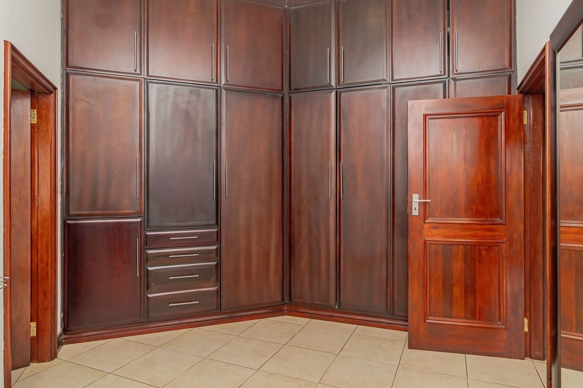A bedroom featuring extensive dark wood built-in cabinetry, tiled flooring, and a solid wooden door.