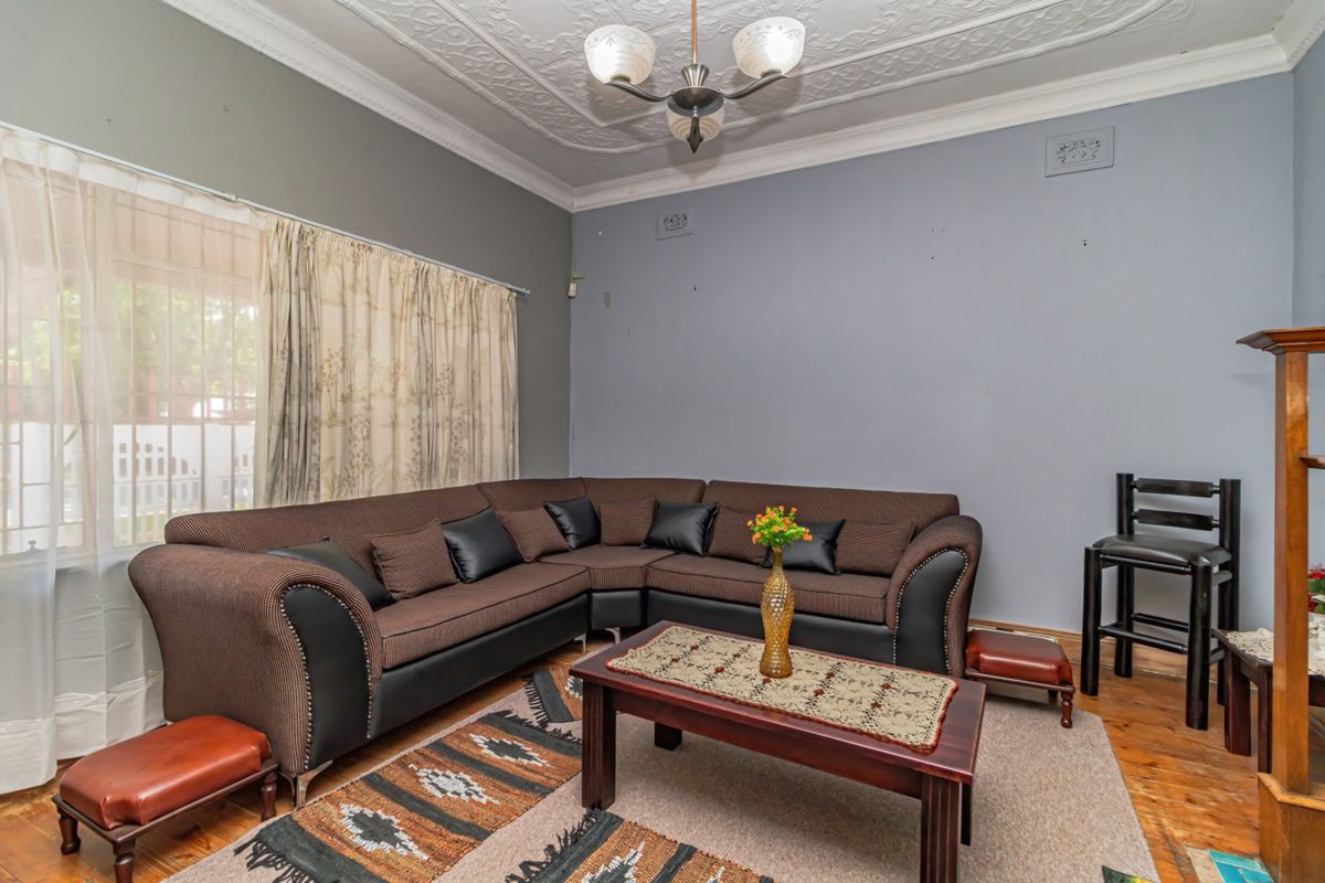 A living room featuring original ornate plaster ceilings, decorative coving, and timber flooring, offering a classic foundation for modern interior updates.