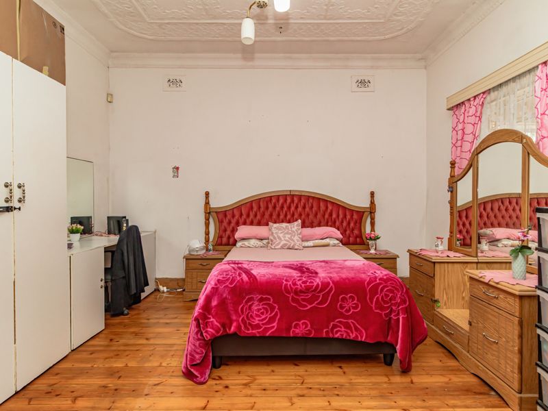 Spacious bedroom featuring original timber flooring and an ornate plaster ceiling, offering a classic foundation for modern updates.