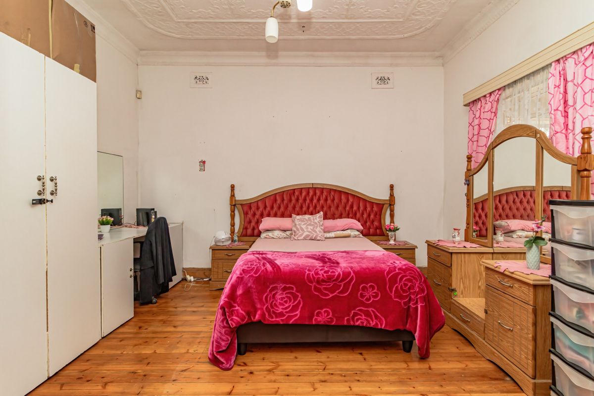 Spacious bedroom featuring original timber flooring and an ornate plaster ceiling, offering a classic foundation for modern updates.