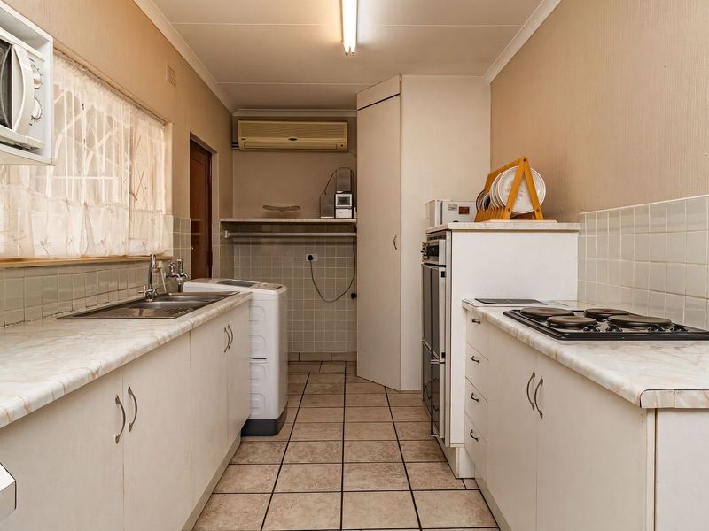 Functional kitchen featuring built-in cabinetry, laminate countertops, a gas hob, and an integrated oven, with tiled flooring and backsplash throughout.