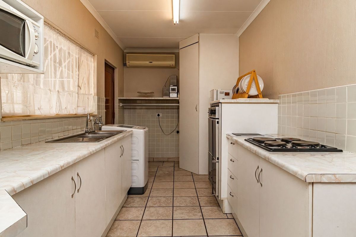 Functional kitchen featuring built-in cabinetry, laminate countertops, a gas hob, and an integrated oven, with tiled flooring and backsplash throughout.