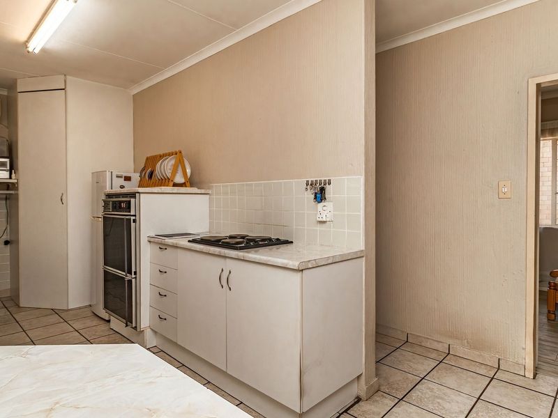 A functional kitchen area featuring built-in cabinetry, a hob, and an oven, with tiled flooring and a neutral color palette.