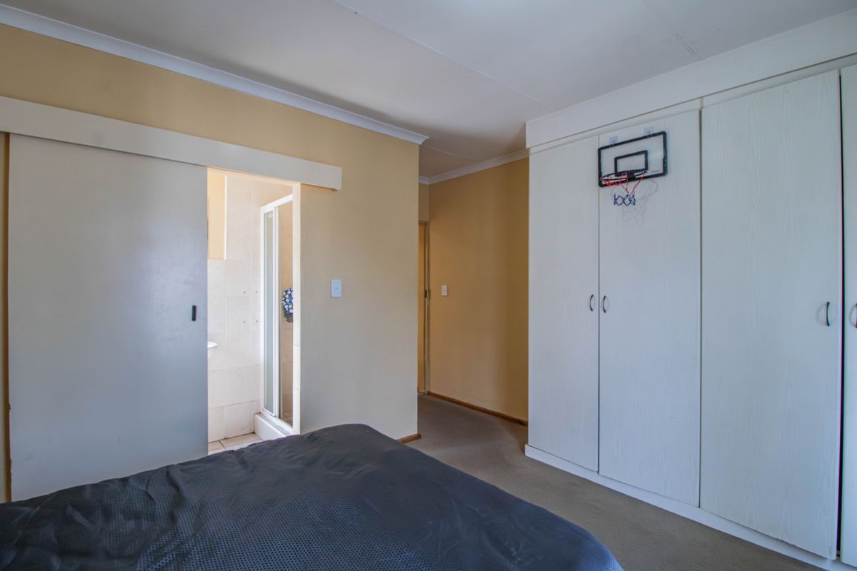Bedroom featuring built-in cupboards and an en-suite bathroom access point with a sliding door.
