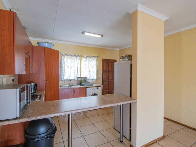 A functional kitchen featuring laminate cabinetry, a breakfast bar, tiled flooring, and integrated laundry plumbing, offering a practical layout for daily use.