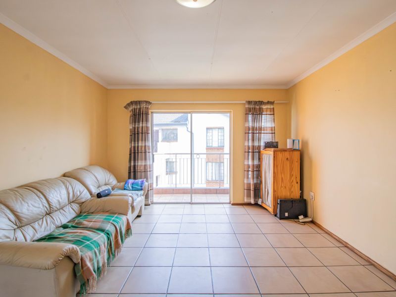 A living room featuring tiled flooring and a sliding glass door providing access to an outdoor balcony area.