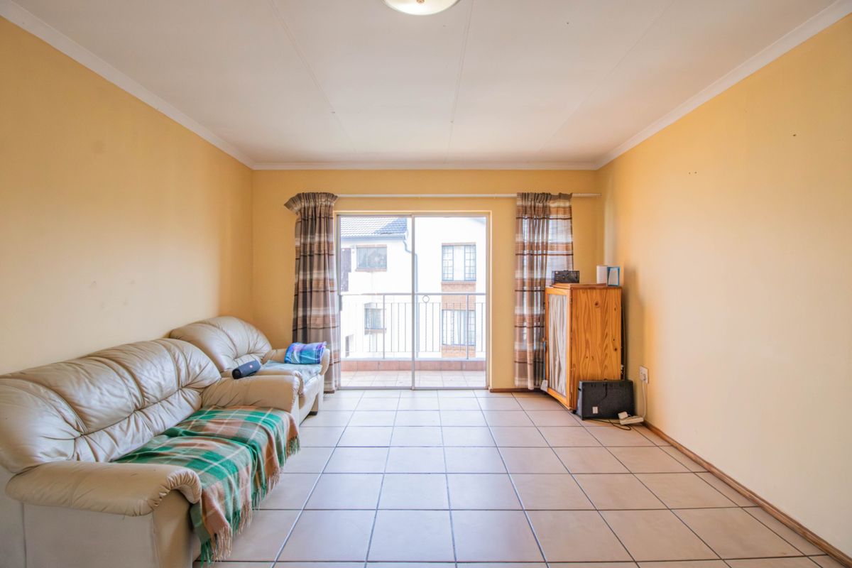 A living room featuring tiled flooring and a sliding glass door providing access to an outdoor balcony area.